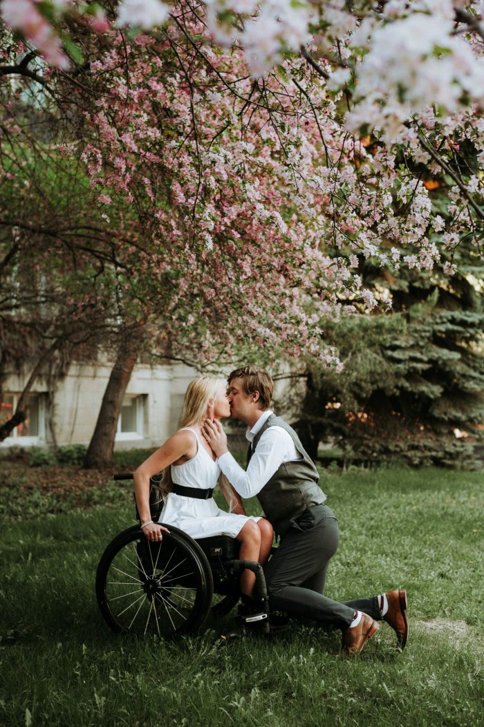 mariée en fauteuil roulant embrassant son mari sous des fleurs