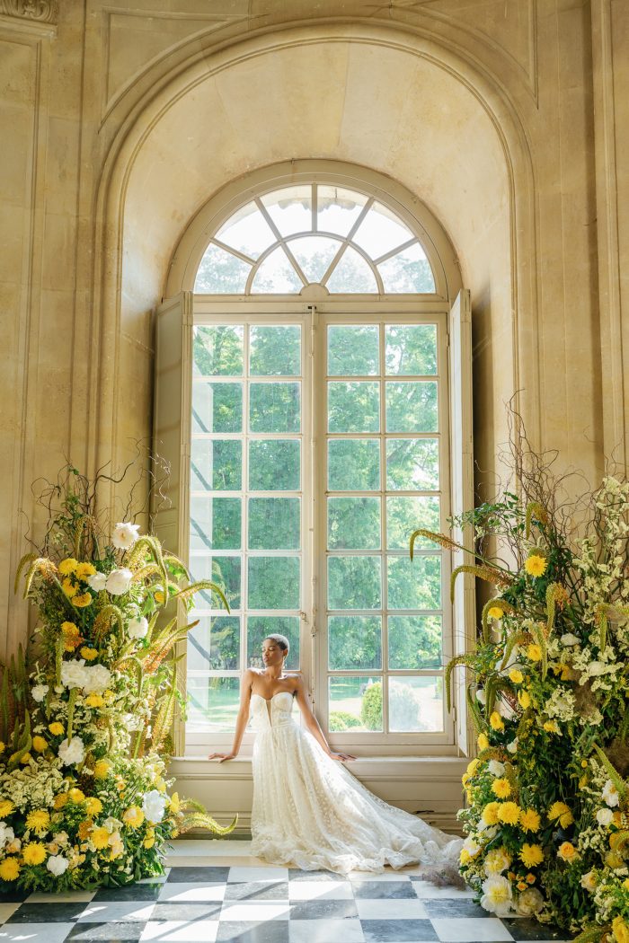 styled shoot bride in large window with yellow florals