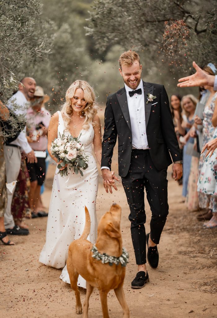 bride and groom walking down the aisle with their dog 