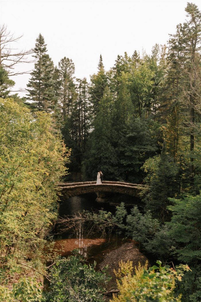 long shot of wedding couple on bridge in the woods
