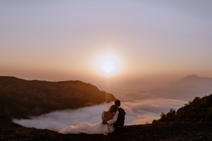 wedding couple sitting above clouds