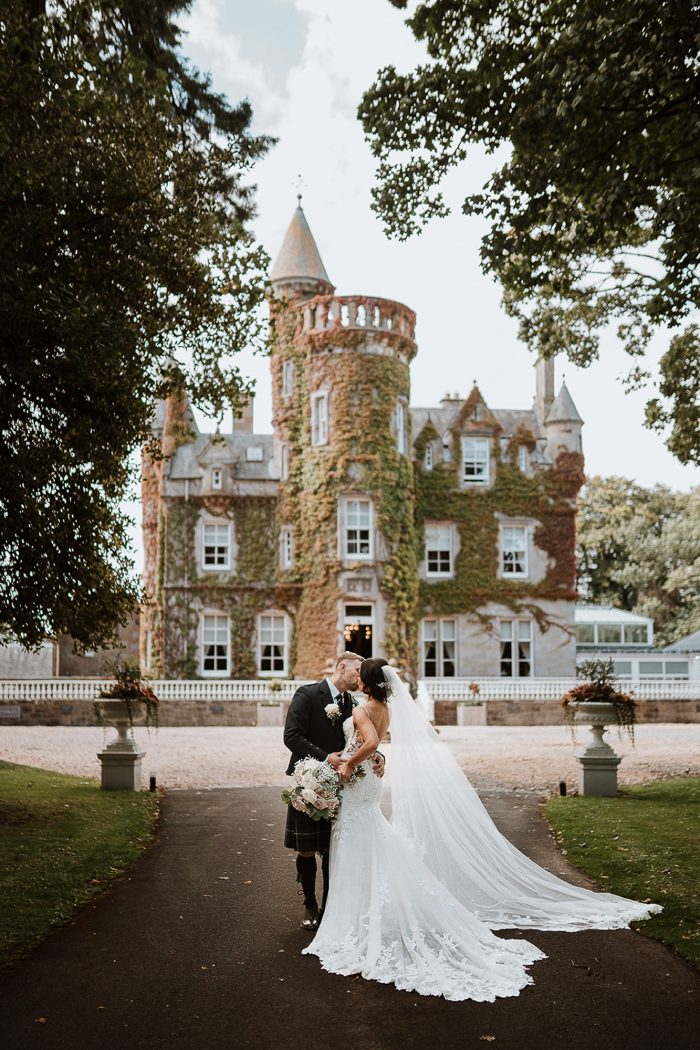 wedding couple kissing in front of a castle