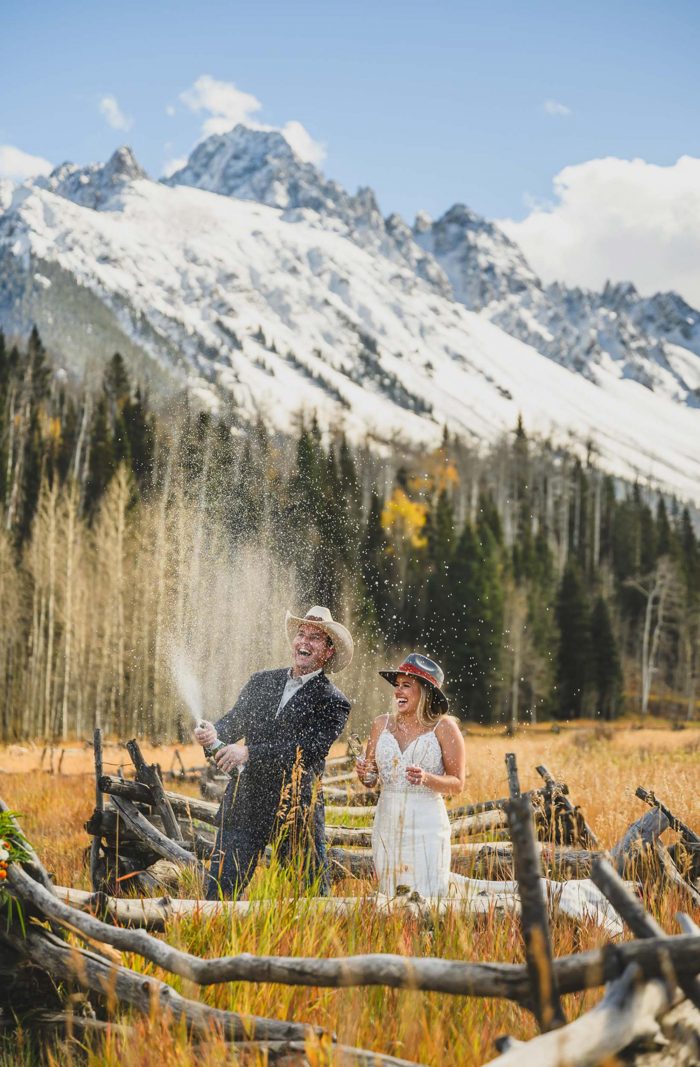 couple popping champagne in colorado mountains