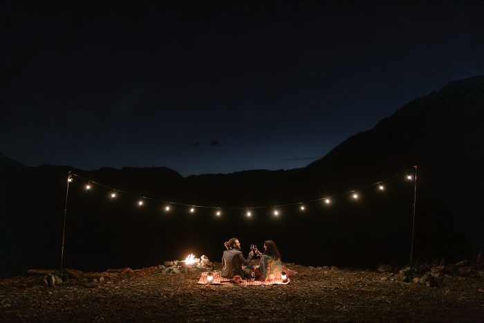 couple picnicking at night under string lights